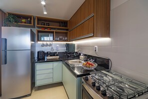 A modern kitchen with a stainless steel refrigerator, a gas stove, and a coffee maker. - Beautiful apartment in Praia do Forte, near the best beach. (Mata de São João)