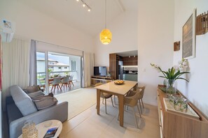 A modern apartment with a dining area, kitchen, and a balcony with a view. - Beautiful apartment in Praia do Forte, near the best beach. (Mata de São João)