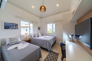 A modern hotel room with two beds, a desk, a TV, and a large window. - Beautiful apartment in Praia do Forte, near the best beach. (Mata de São João)