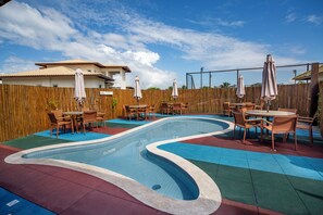 A swimming pool with a wooden fence and outdoor seating. - Beautiful apartment in Praia do Forte, near the best beach. (Mata de São João)