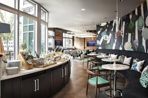 Un restaurante moderno con bufé, zona de estar y amplios ventanales.