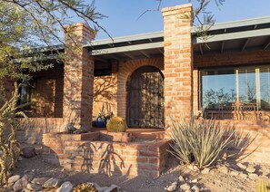 A brick house with a large arched entrance, a covered porch, and a window with blinds. - Midcentury w/ pool, mountain view in quiet neighborhood-gem show, UofA, downtown (Tucson)