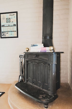 A vintage wood-burning stove with a mantelpiece, books stacked on top, and a framed picture on the wall. - Midcentury w/ pool, mountain view in quiet neighborhood-gem show, UofA, downtown (Tucson)