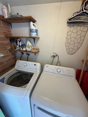 A laundry area with two washing machines, a shelf with cleaning supplies, and a drying rack. - Midcentury w/ pool, mountain view in quiet neighborhood-gem show, UofA, downtown (Tucson)
