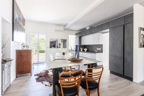 Eine moderne Küche mit einer zentralen Kochinsel, weißen Schränken und einem Essbereich mit Tisch und Stühlen.