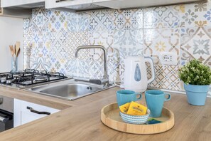 A kitchen with a gas stove, sink, and a kettle on the countertop. - La Terrazza nel Borgo (Marsciano)