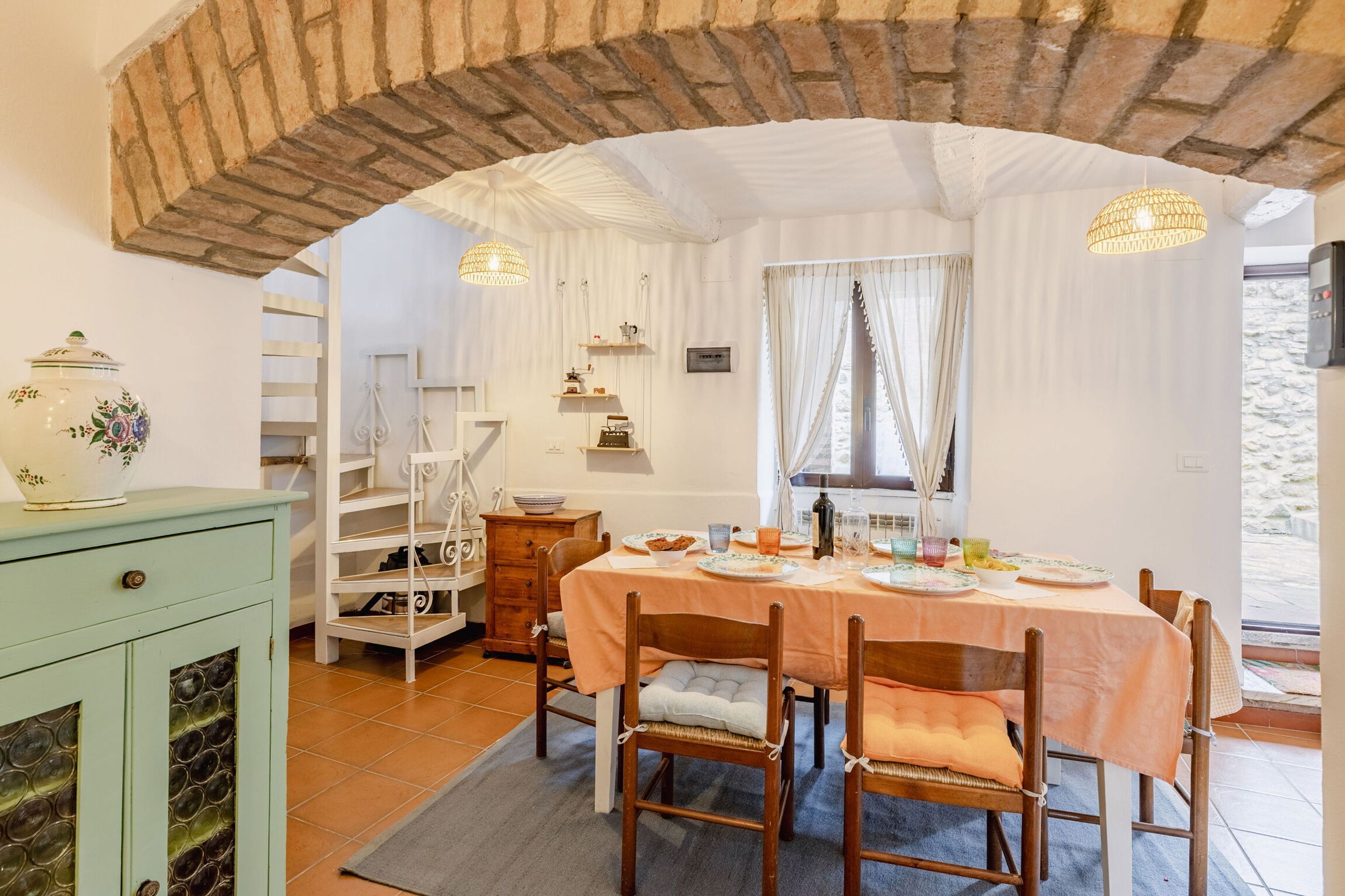 Ein Essbereich mit Tisch für vier Personen, Stühlen, einem Buffetschränkchen und einer sichtbaren Küche im Hintergrund.