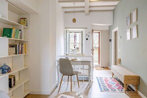 A hallway with a white desk, chair, and bookshelf, leading to a door. - La Terrazza nel Borgo (Marsciano)