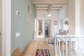 A hallway with a bench, a dining area with a table and chairs, and a kitchen visible through an open door. - La Terrazza nel Borgo (Marsciano)