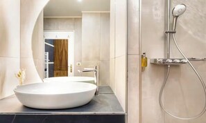 A modern bathroom with a large oval sink, a shower with a handheld showerhead, and a towel rack. - A REFINED CONTEMPORARY DESIGN WITH THE TIMELESS CHARM OF PARIS - MARAIS (Paris)