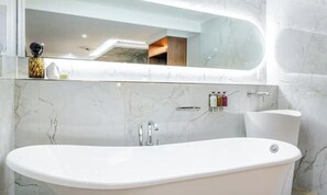 A modern bathroom with a freestanding bathtub, a large mirror, and marble walls. - A REFINED CONTEMPORARY DESIGN WITH THE TIMELESS CHARM OF PARIS - MARAIS (Paris)