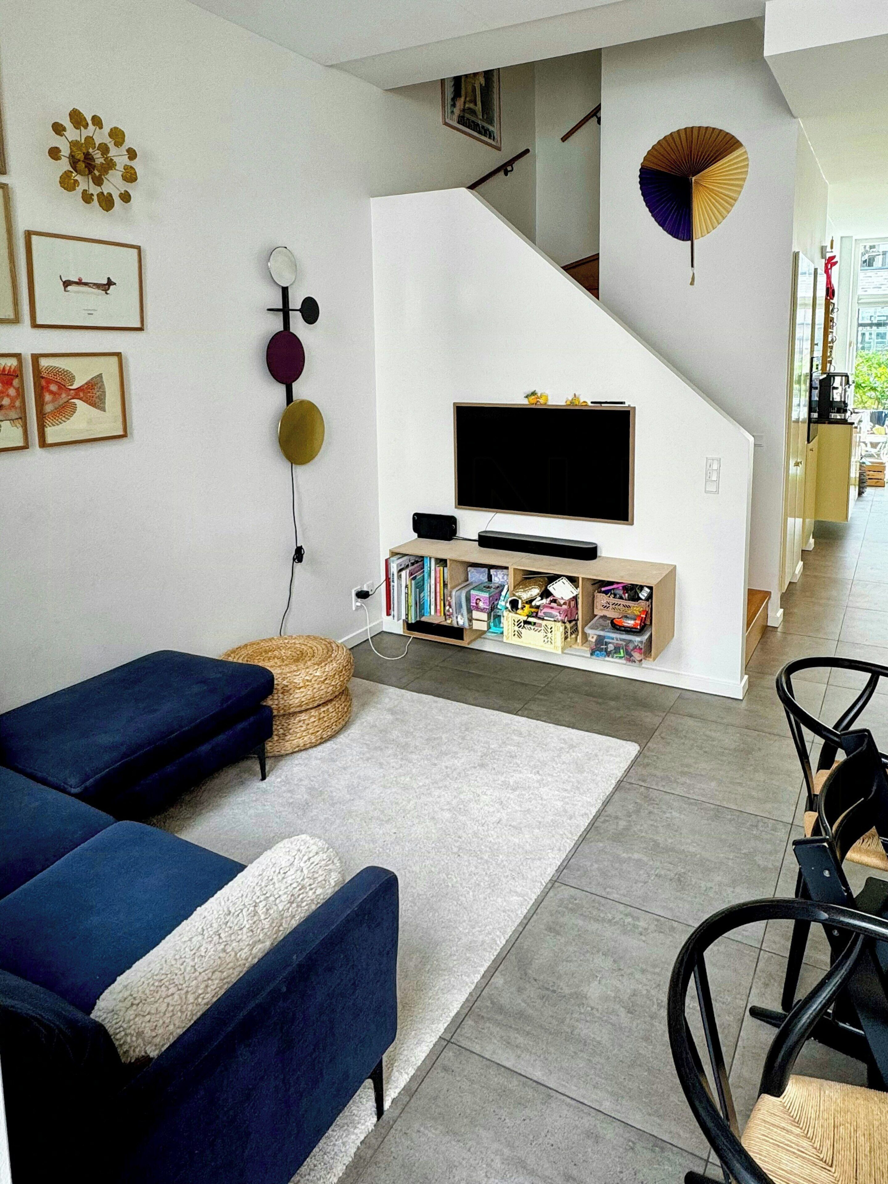 En moderne stue med sofa, fjernsyn og reol.