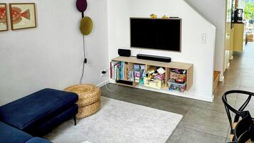 En moderne stue med sofa, fjernsyn og reol.
