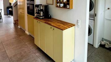A kitchen with a built-in coffee machine, a wooden countertop, and a wall-mounted mug rack.