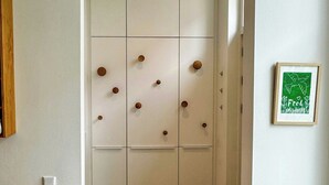 Een hal met een witte kast, een lijst met een foto aan de muur en een bruin vloerkleed.