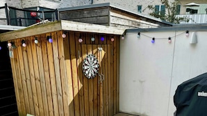 Een terras met een dartbord, een tafel en stoelen.