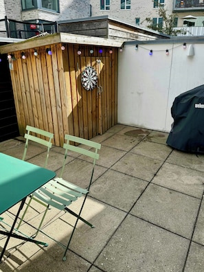A patio area with a dartboard, a table, and chairs. - House near Havnevigen with terrace and courtyard (København)