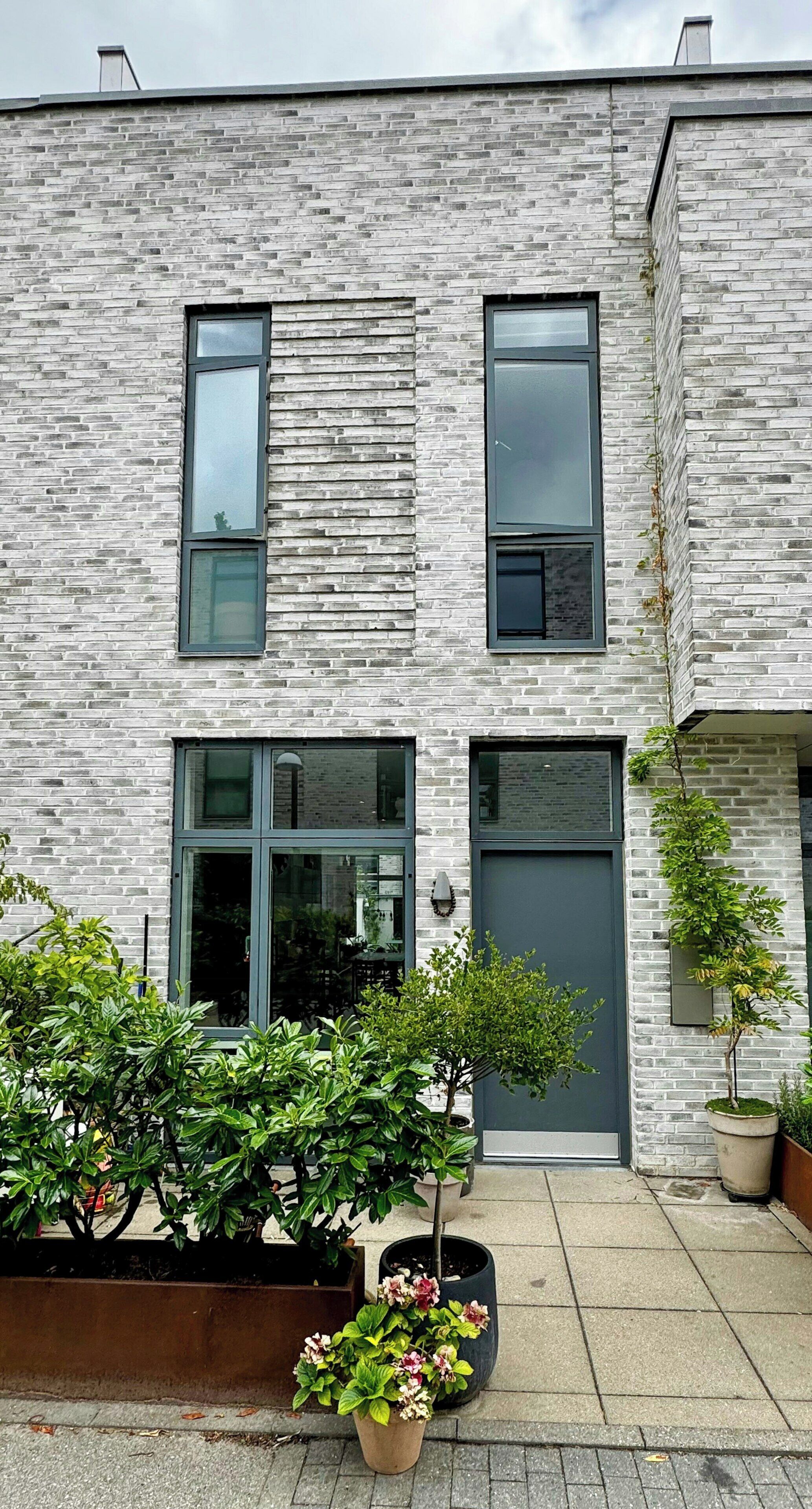 En moderne bygning med murstensfacade, store vinduer og et fladt tag.