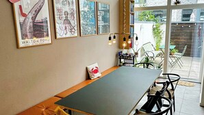 Een eetruimte met een lange tafel, stoelen, een bank en wanddecoratie.