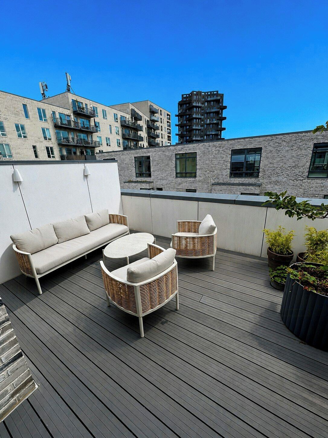 An outdoor deck with a sofa, chairs, and potted plants.