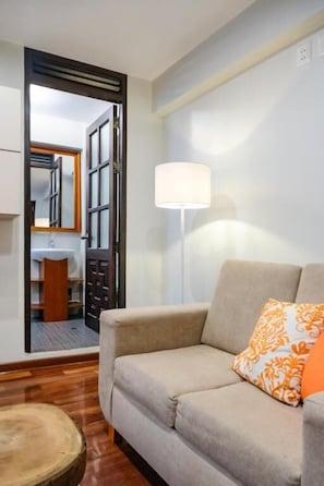 A room with a sofa, a lamp, and a wooden table. - Ayra Hotel Boutique (Písac)