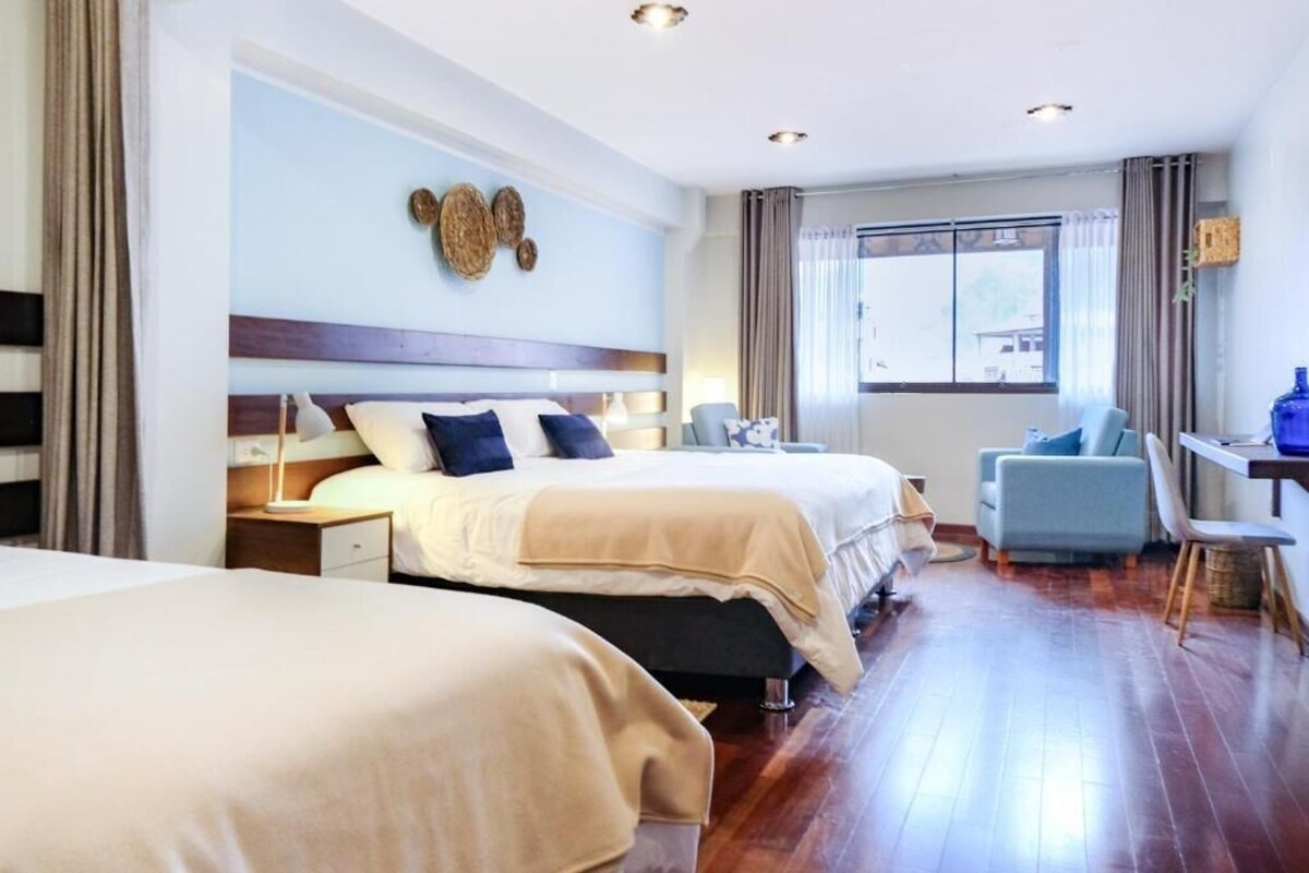 A hotel room with two beds, a desk, and a chair.