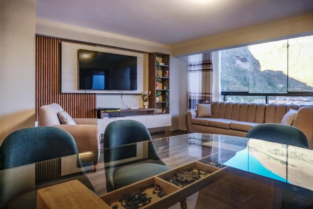 Una sala de estar moderna con una mesa de centro de vidrio, sofás y un televisor de pantalla plana montado en la pared.