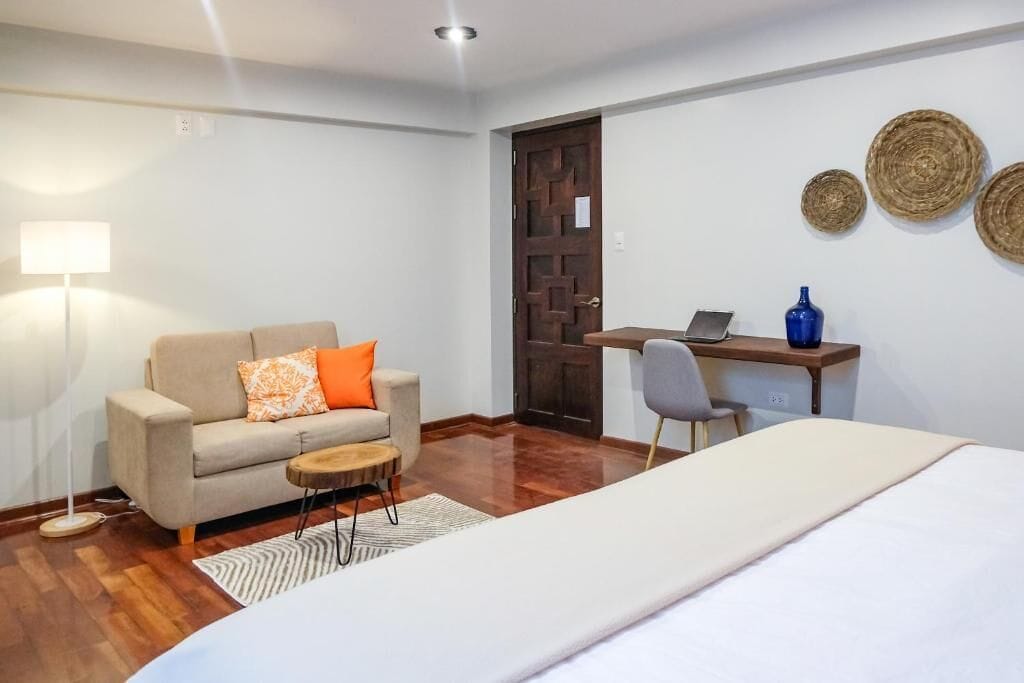 Une chambre d’hôtel avec un lit, un canapé, un bureau et un ordinateur portable.