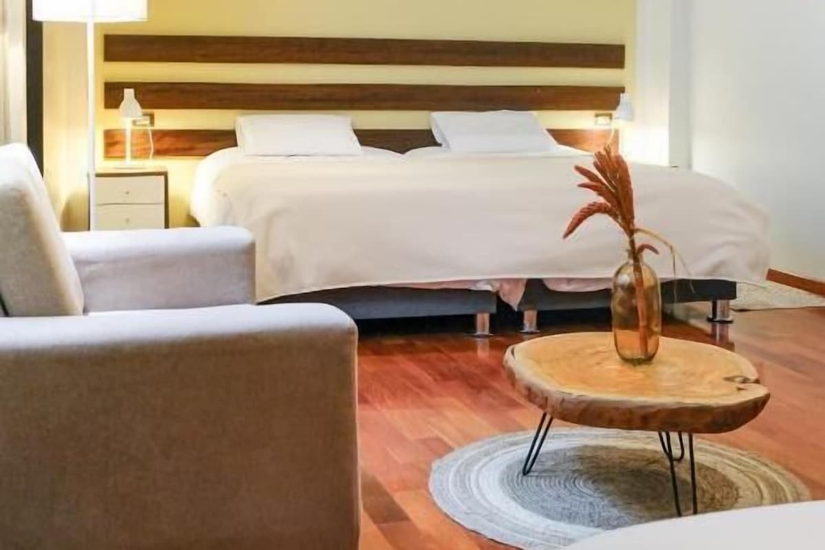 A hotel room with a bed, two bedside tables, a sofa, and a round coffee table.