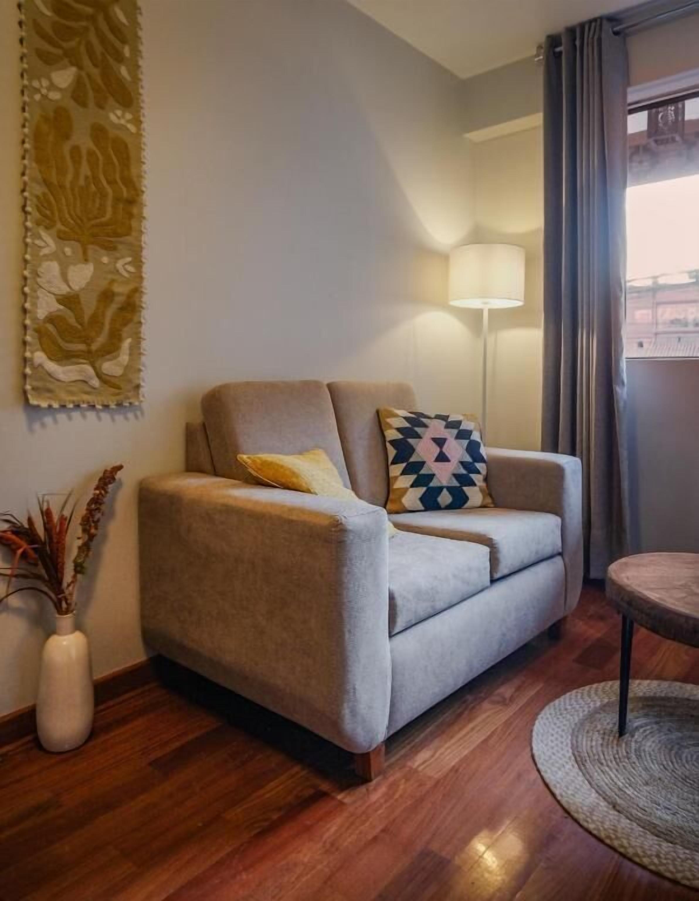 Un salon comprenant un canapé, une lampe, une table ronde et un élément décoratif mural.