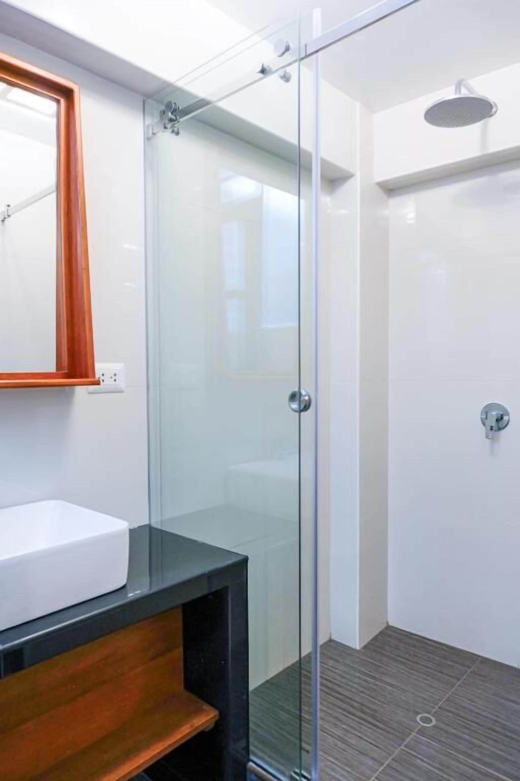Une salle de bain moderne avec une douche à parois de verre, un lavabo blanc et un meuble-lavabo en bois.