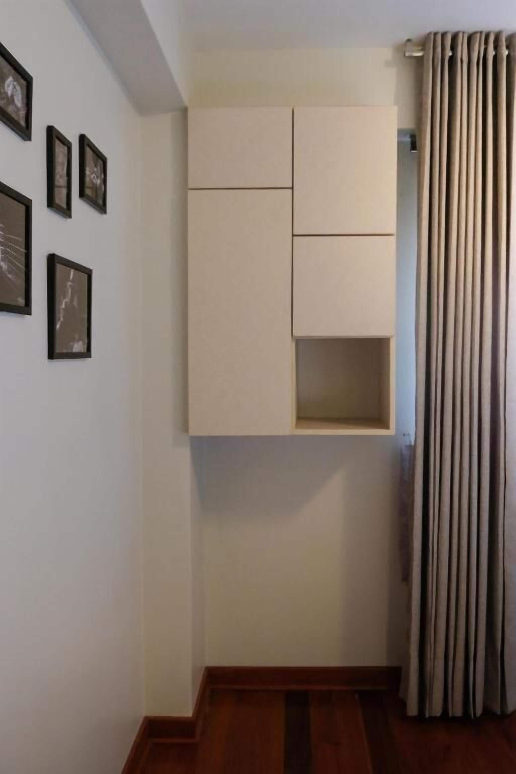 Une pièce d’angle avec un placard intégré, un plancher en bois et un rideau.
