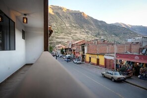 Vista de una calle con edificios, una montaña al fondo y un coche estacionado al lado.