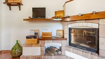 A fireplace with a stone surround, a television on a shelf above, and wine boxes on the mantel.