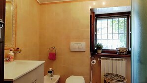 A bathroom with a toilet, bidet, vanity, and a window with a view. - Stone chalet in a medieval village, with an enchanting view of the lake (Vagli Sotto)