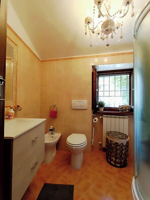 A bathroom with a toilet, bidet, vanity, and a window with a view. - Stone chalet in a medieval village, with an enchanting view of the lake (Vagli Sotto)