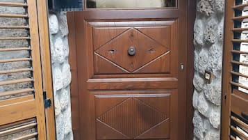 A wooden door with a diamond pattern, a mailbox, and a doormat.