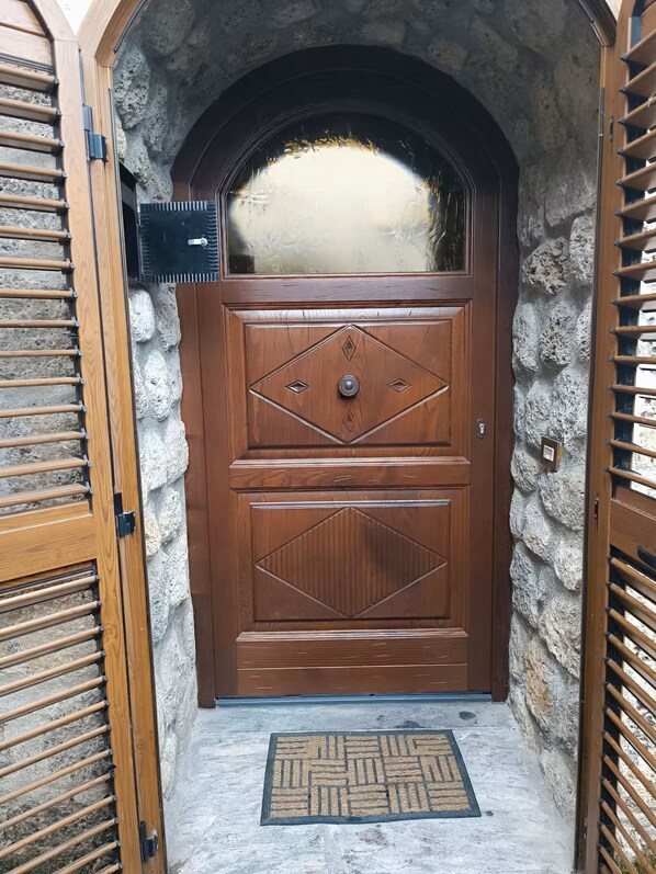 A wooden door with a diamond pattern, a mailbox, and a doormat.