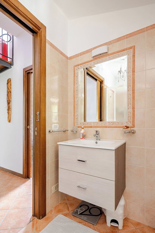 A bathroom with a white vanity, a mirror with an ornate frame, and a towel rack.