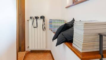 A hallway with a tiled floor, a radiator, a shelf with books, a camera, and a fire extinguisher.