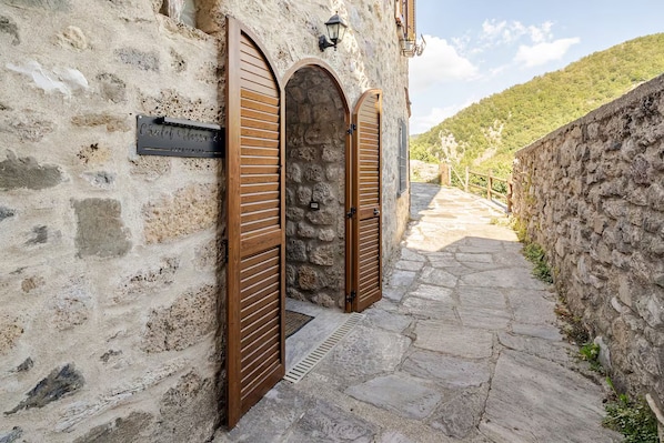 A stone building with two wooden doors, a stone pathway, and a stone wall.