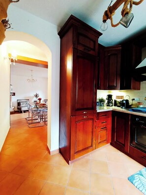 A kitchen with wooden cabinets, a dining area with a table and chairs, and a chandelier.