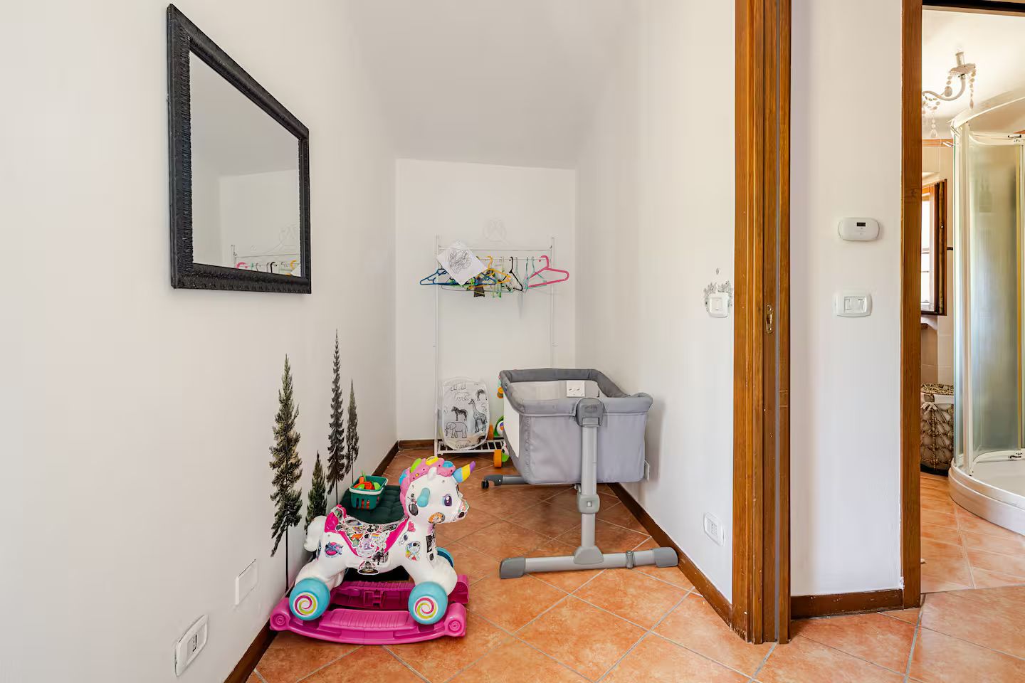Ein Spielbereich für Kinder mit einem Schaukelpferd, einer Wickelstation und einem Spiegel an der Wand.