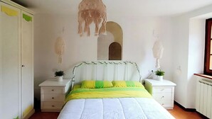 A bedroom with a bed, nightstands, a hanging light fixture, and a wardrobe. - Stone chalet in a medieval village, with an enchanting view of the lake (Vagli Sotto)