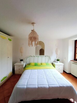 A bedroom with a bed, nightstands, a hanging light fixture, and a wardrobe. - Stone chalet in a medieval village, with an enchanting view of the lake (Vagli Sotto)