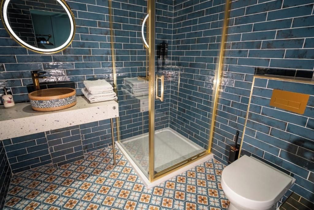 Een badkamer met een glazen douchecabine, een wit toilet en een wastafel met een decoratieve kom.