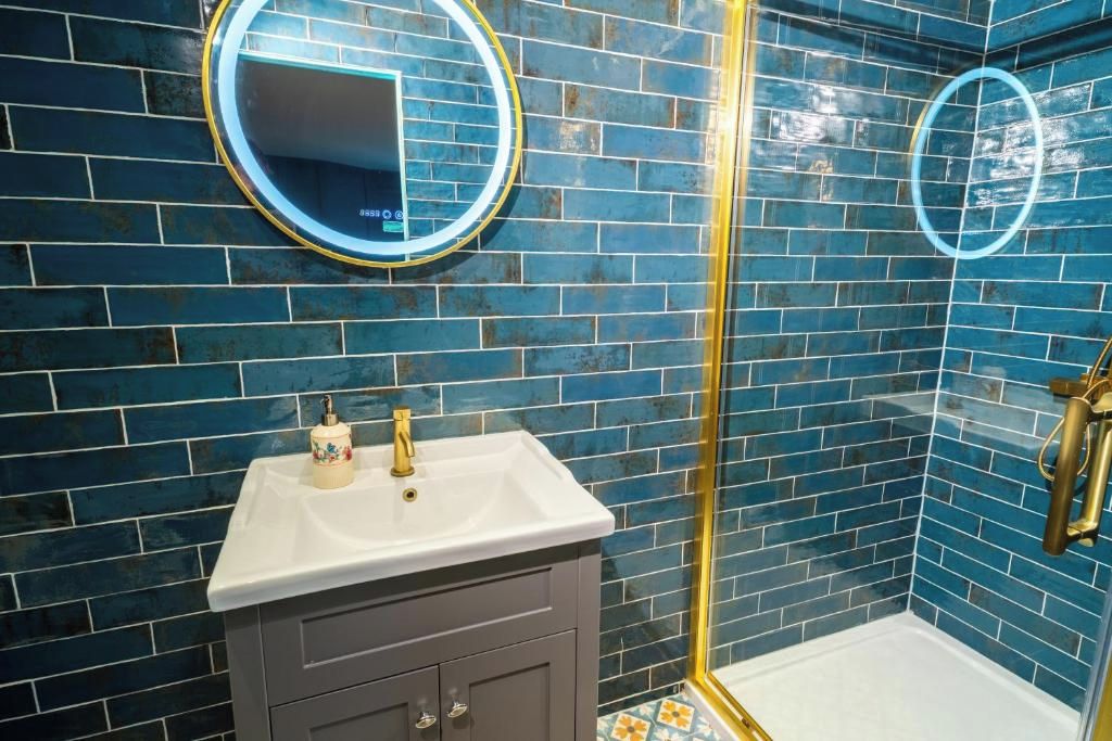 A bathroom with blue-tiled walls, a white sink, and a shower enclosure.