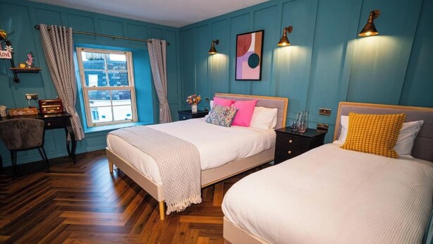A bedroom with two beds, a desk, and a window with curtains. - Woolen house  (MO)