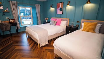 A bedroom with two beds, a desk, and a window with curtains.