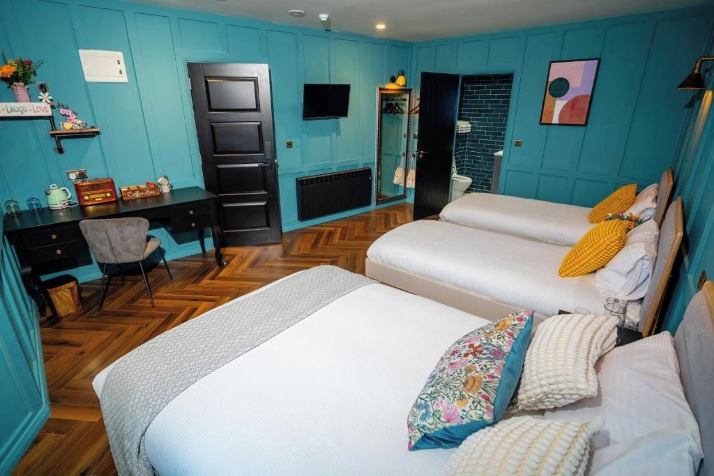 A room with two beds, a desk, a chair, a television, and a mirror.